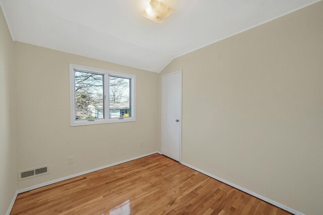 unfurnished room featuring baseboards, visible vents, vaulted ceiling, and light wood finished floors