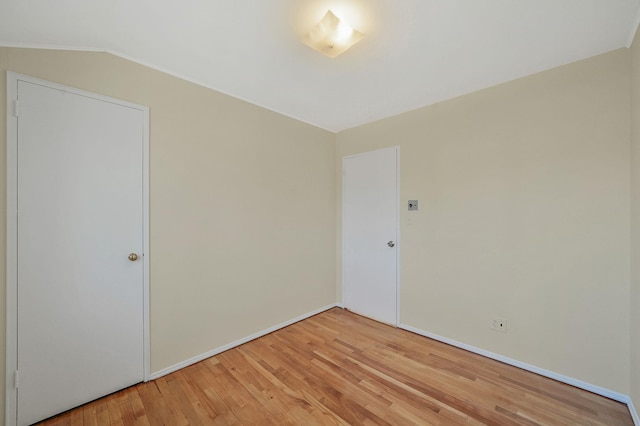 spare room with lofted ceiling and light wood-style flooring