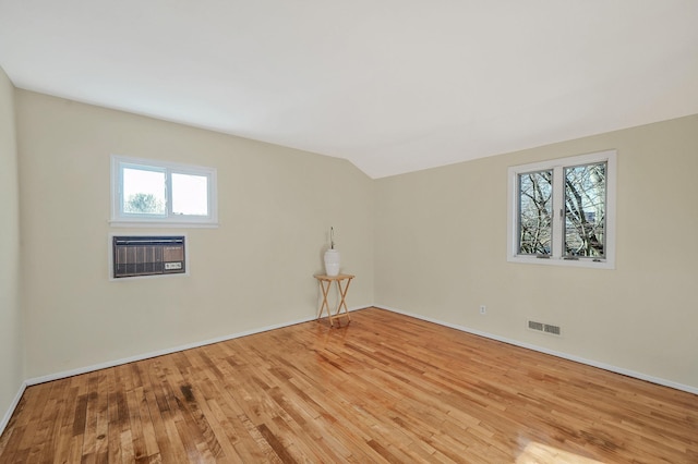 empty room with a wealth of natural light, visible vents, and wood finished floors