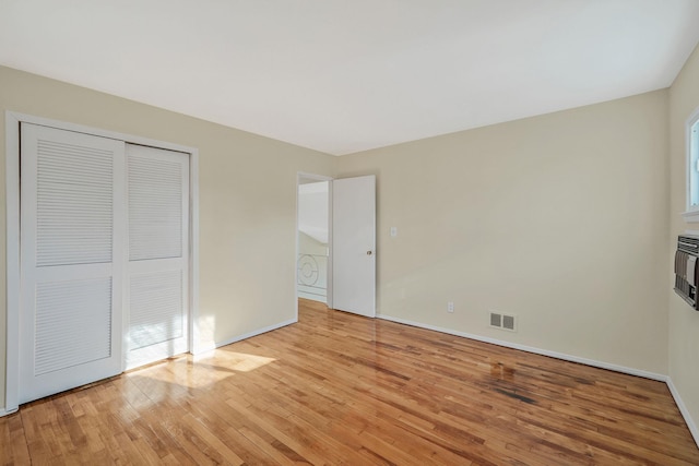 unfurnished bedroom with a closet, visible vents, light wood-style flooring, and baseboards