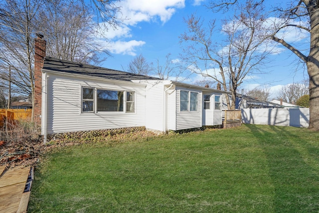 exterior space featuring a chimney, fence, and a yard