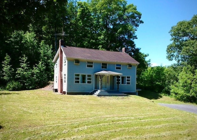 colonial house featuring a chimney and a front yard