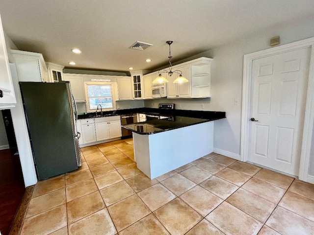 kitchen with range with electric stovetop, freestanding refrigerator, a peninsula, white microwave, and dishwasher