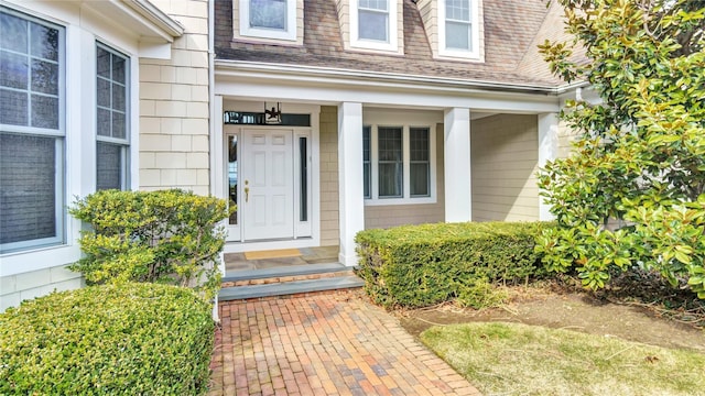 view of exterior entry featuring roof with shingles