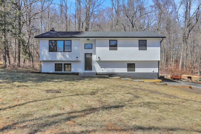 raised ranch with a chimney, a front lawn, and entry steps