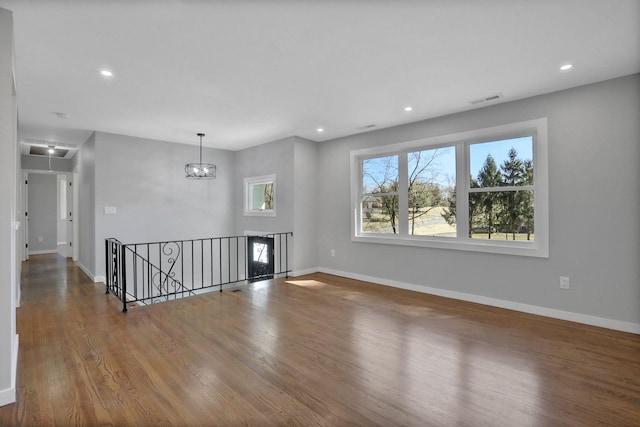 spare room with visible vents, baseboards, attic access, and wood finished floors