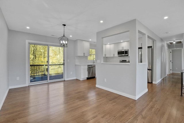 kitchen featuring light countertops, decorative backsplash, white cabinets, stainless steel appliances, and dark wood-style flooring