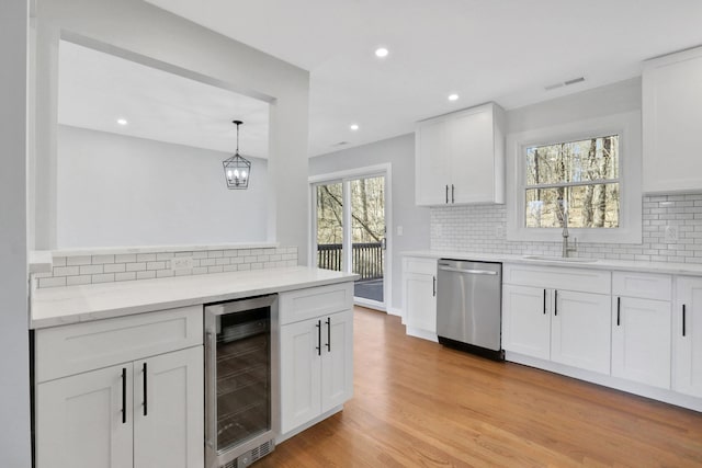 kitchen featuring visible vents, light wood-type flooring, beverage cooler, a sink, and dishwasher