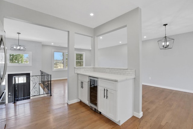 interior space featuring decorative light fixtures, light wood-style floors, wine cooler, and a notable chandelier