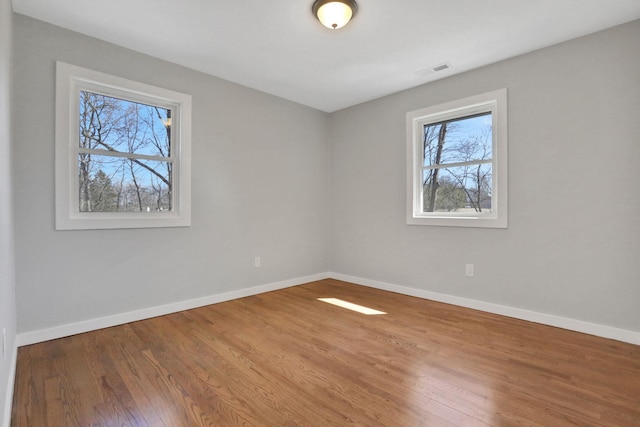 unfurnished room featuring visible vents, baseboards, and wood finished floors