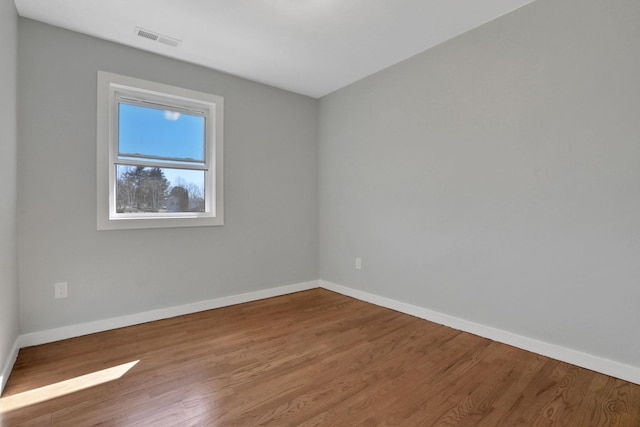 unfurnished room featuring visible vents, baseboards, and wood finished floors