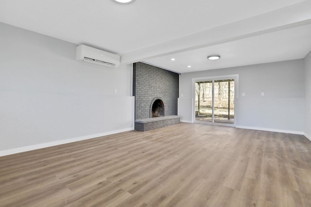 unfurnished living room featuring baseboards, light wood finished floors, a brick fireplace, and a wall mounted AC