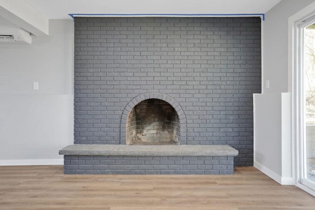 interior details with a wall unit AC, wood finished floors, and baseboards