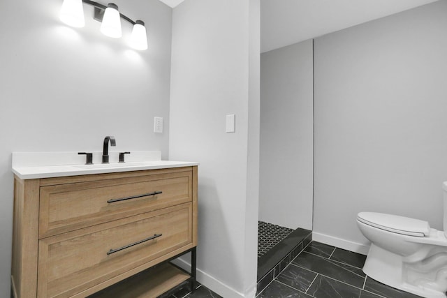 bathroom featuring baseboards, toilet, vanity, and a walk in shower