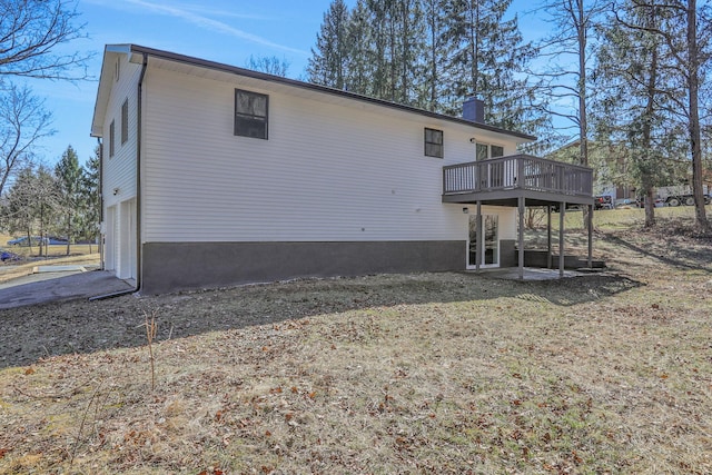 rear view of house with a garage, a chimney, and a wooden deck