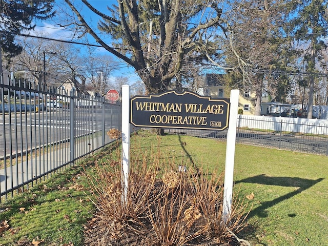 community / neighborhood sign featuring a lawn and fence