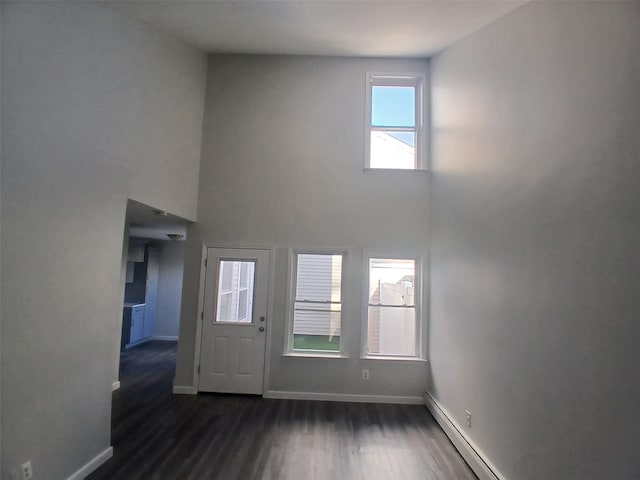 foyer entrance with dark wood-style flooring, baseboards, a towering ceiling, and baseboard heating