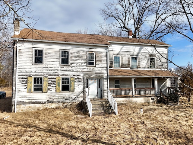 view of front facade featuring covered porch and a chimney