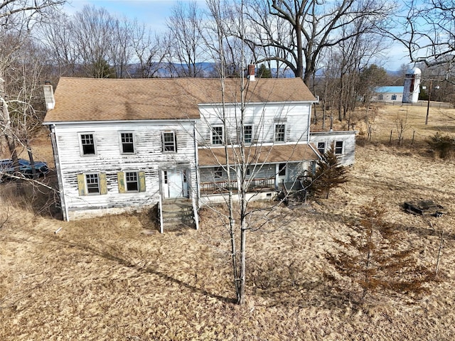 rear view of property featuring a porch and a chimney