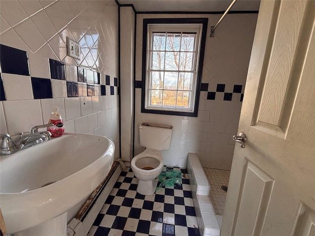 full bathroom with toilet, tiled shower, tile patterned floors, tile walls, and a sink