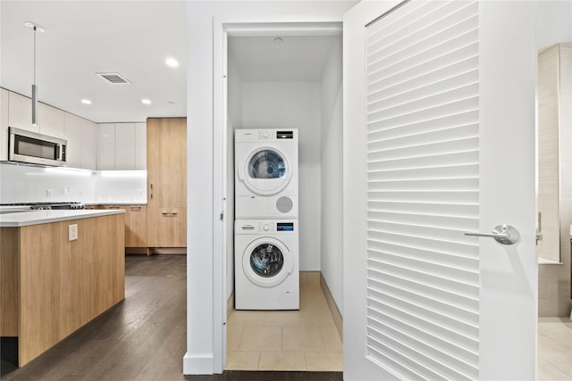 washroom with recessed lighting, laundry area, wood finished floors, visible vents, and stacked washer / drying machine