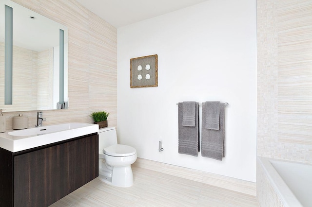 bathroom featuring a tub to relax in, toilet, tile patterned flooring, vanity, and tile walls