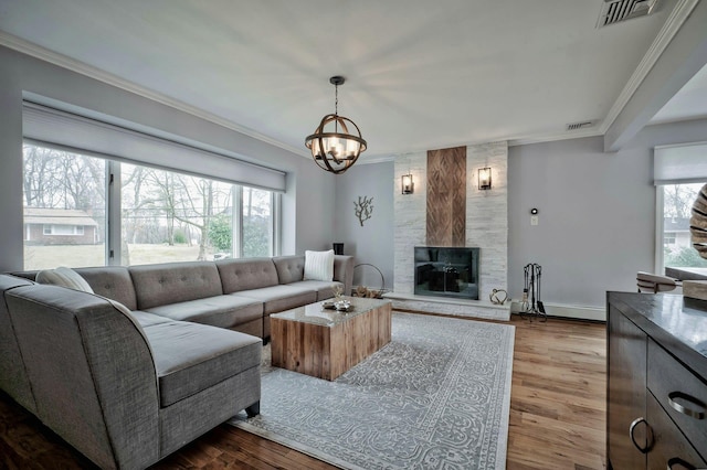 living area with dark wood-type flooring, a fireplace, visible vents, and crown molding