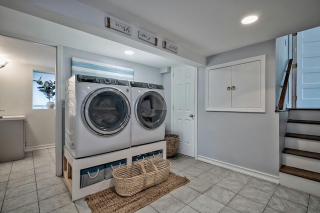 laundry area with laundry area, washer and clothes dryer, light tile patterned flooring, and baseboards