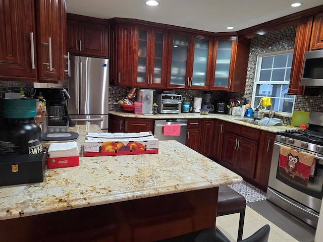 kitchen with appliances with stainless steel finishes, backsplash, and light stone countertops