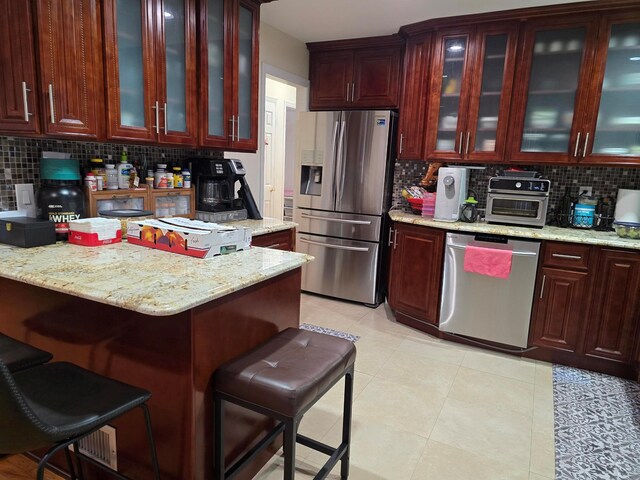 kitchen featuring appliances with stainless steel finishes, dark brown cabinets, backsplash, and a breakfast bar area