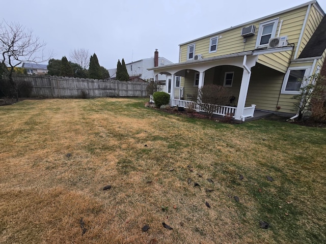 view of yard featuring covered porch, a wall mounted AC, and fence