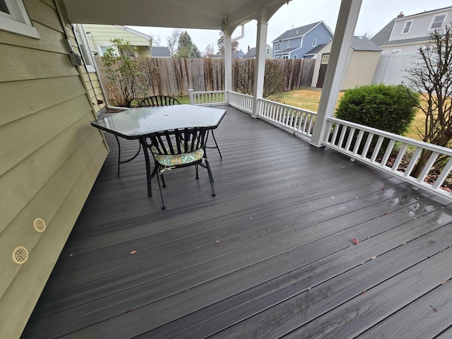 deck featuring an outbuilding, outdoor dining space, fence, and a storage unit