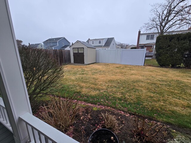 view of yard featuring a storage shed, an outdoor structure, a fenced backyard, and a residential view