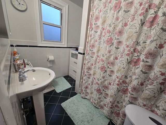 bathroom with curtained shower, toilet, a wainscoted wall, tile walls, and tile patterned floors