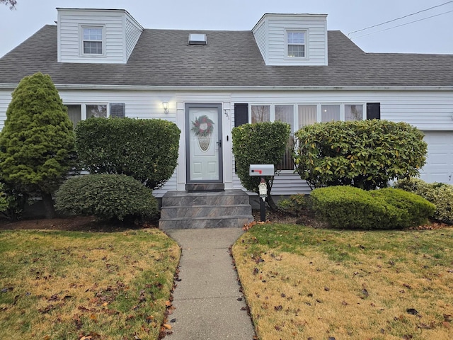 cape cod home with a front lawn and roof with shingles