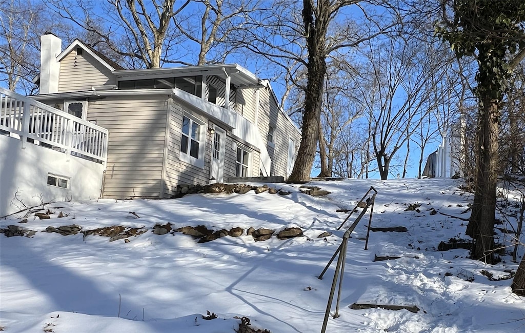 snow covered property with a garage and a chimney