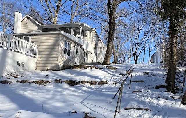 snow covered property with a garage and a chimney