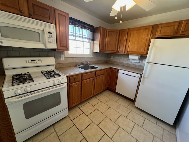 kitchen featuring white appliances, tasteful backsplash, brown cabinets, and a sink