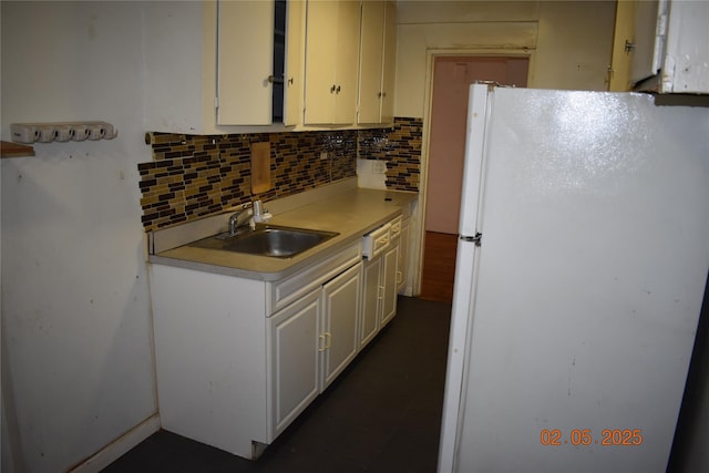 kitchen featuring freestanding refrigerator, light countertops, a sink, and decorative backsplash