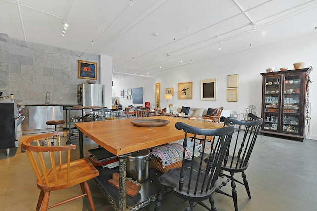 dining area featuring wet bar, concrete floors, and rail lighting