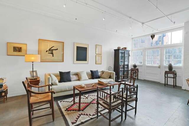 living room with rail lighting, concrete flooring, and baseboards