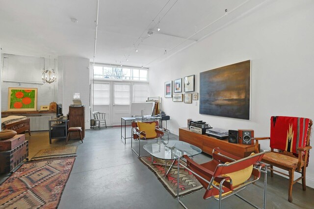 living room featuring rail lighting, radiator heating unit, and concrete flooring