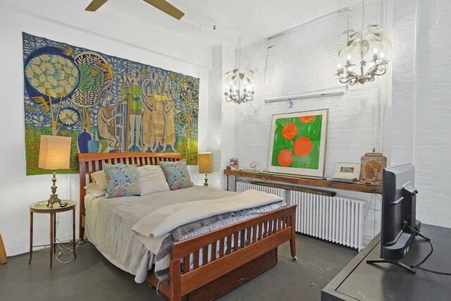 bedroom with ceiling fan with notable chandelier, concrete flooring, brick wall, and radiator heating unit