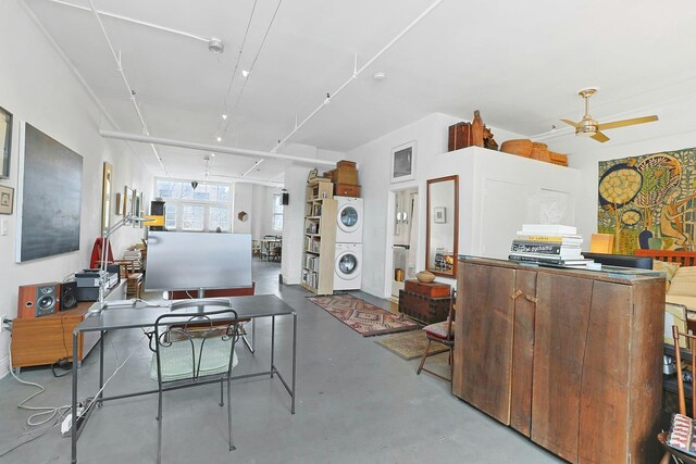 interior space featuring stacked washer / dryer, concrete floors, and ceiling fan