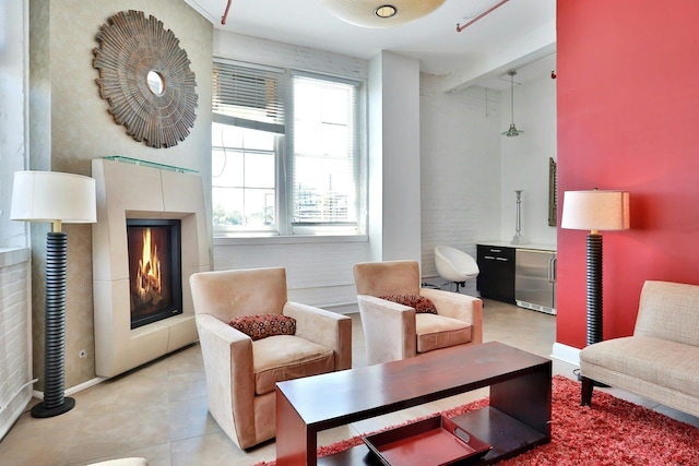 living area featuring light tile patterned flooring, a warm lit fireplace, and baseboards