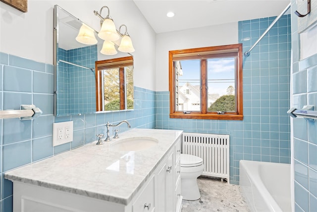 bathroom featuring vanity, radiator heating unit, tile walls, toilet, and a washtub