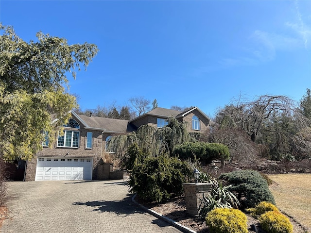 view of front of property with brick siding, decorative driveway, and a garage