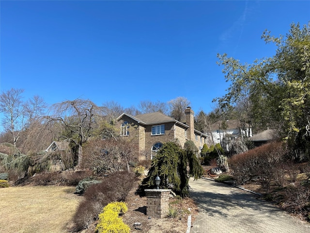 view of side of property with a chimney and decorative driveway