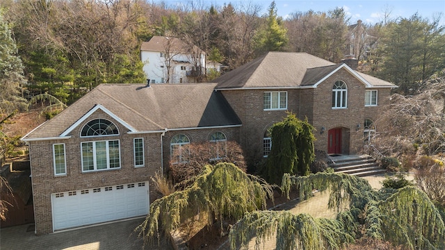 traditional home with aphalt driveway, brick siding, and a garage