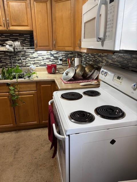 kitchen featuring white appliances, light countertops, backsplash, and brown cabinetry